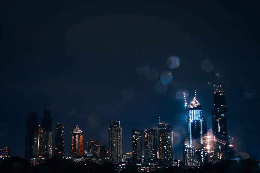 Jakarta skyline at night with illuminated skyscrapers and city lights against dark blue sky.
