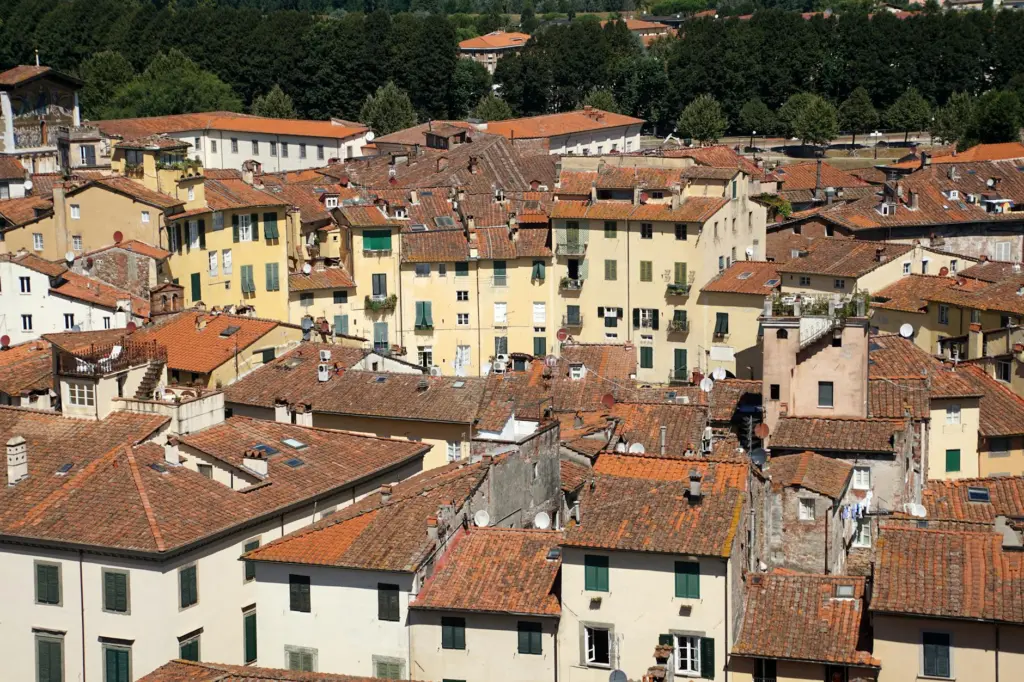 Aerial view of a historic Italian town with terracotta-roofed buildings and yellow facades nestled among green hills.