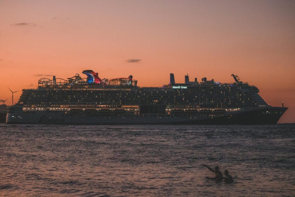 Large cruise ship illuminated at sunset with passengers swimming in foreground waters off Puerto Plata beach.