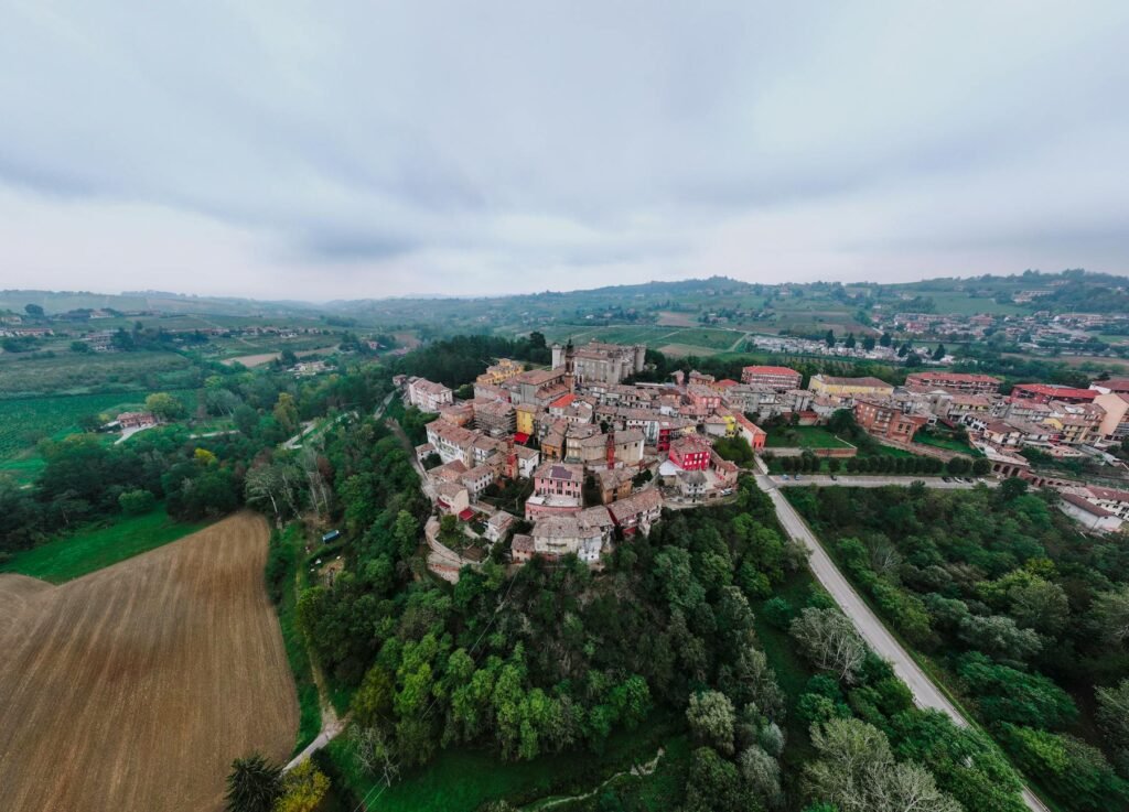 Aerial view of Craco, a historic hilltop village in southern Italy surrounded by green countryside and forests.