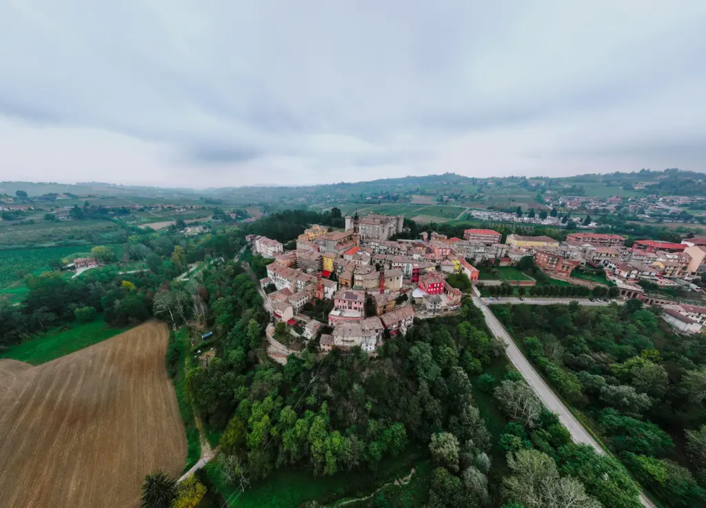 Aerial view of Craco, a historic hilltop village in southern Italy surrounded by green countryside and forests.