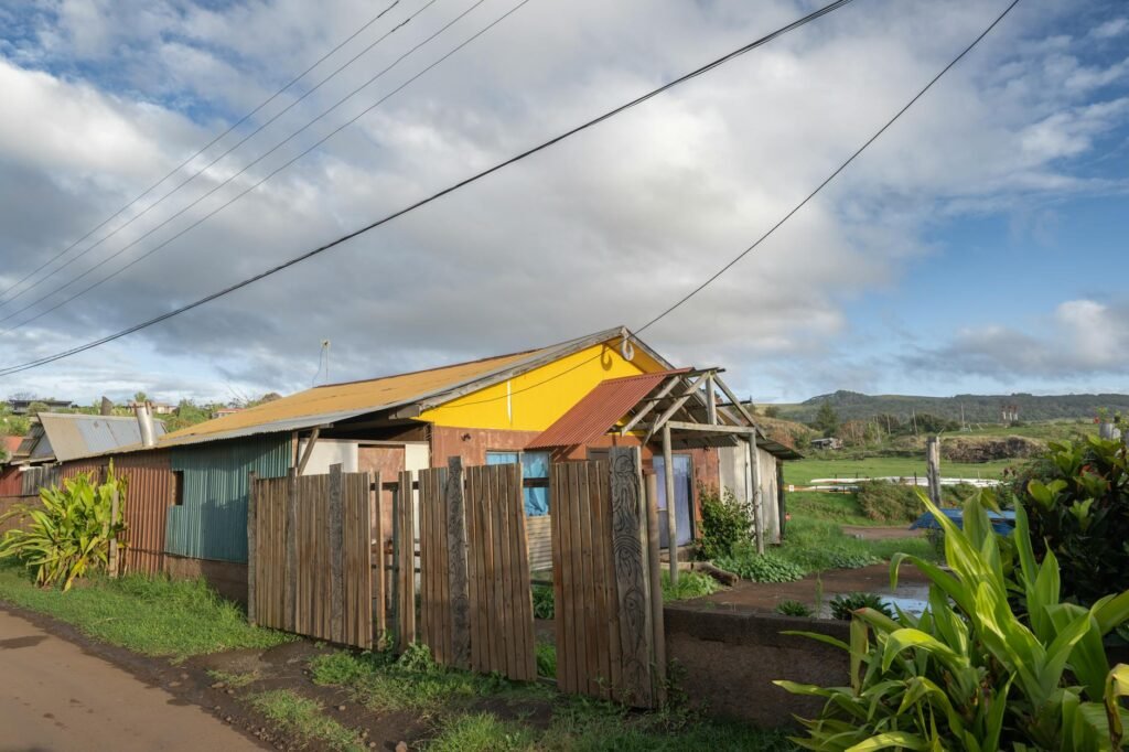 Rustic wooden house with bright yellow roof in rural Chilean countryside landscape.