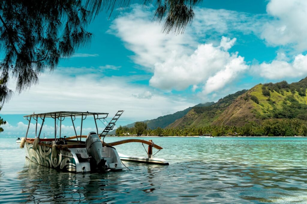 Motorboat anchored in turquoise tropical waters with lush green mountains and palm trees in background.