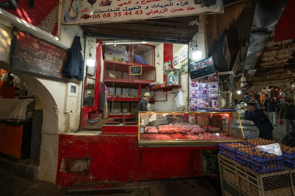 Red meat stall in a Tangier medina market with display cases and vendor inside shop.