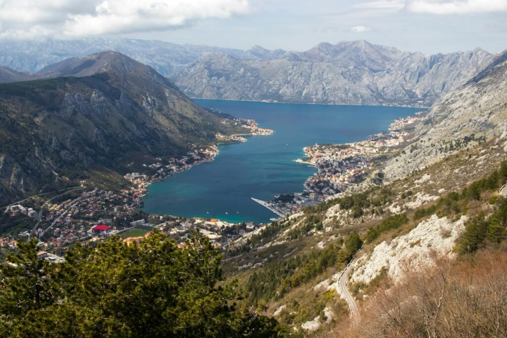 Aerial view of Bay of Kotor surrounded by dramatic mountains with coastal towns nestled along turquoise waters.