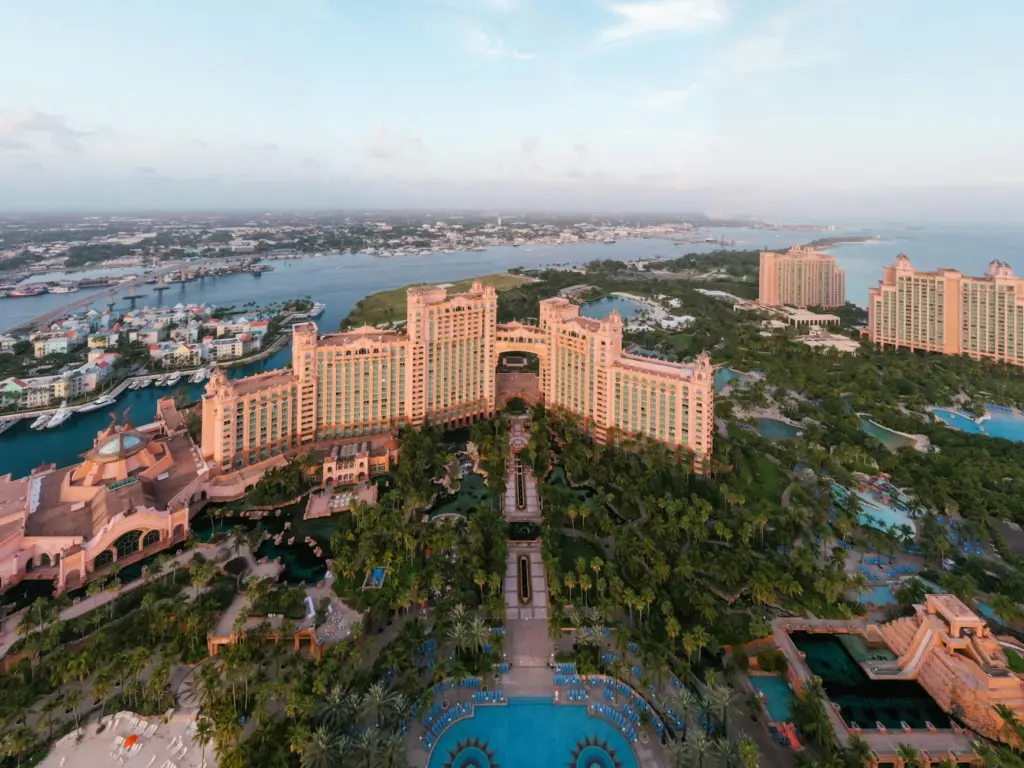 Aerial view of Atlantis Resort in Nassau with pink buildings, pools, and harbor surrounded by turquoise water.